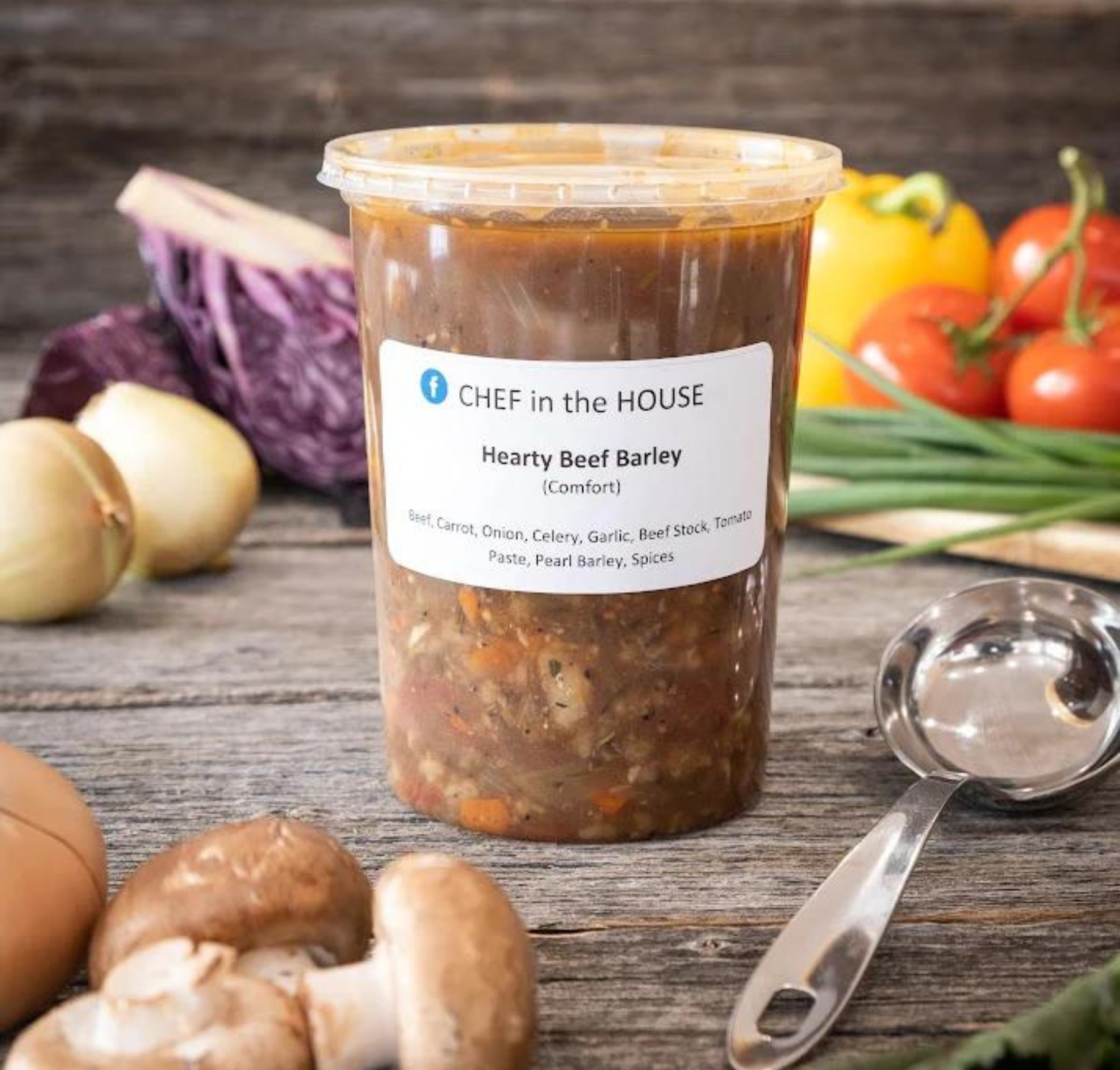 A bowl of hearty beef barley soup with visible ingredients including carrots, onions, and parsley.