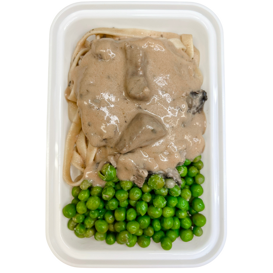 A prepared meal consisting of beef strips with sour cream mushroom gravy on top, served with fettucine noodles and green peas, presented in a white take-out container.