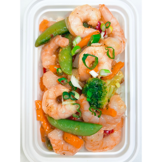 A prepared dish of Mango Garlic Shrimp with colorful vegetables such as broccoli and snap peas, served atop white rice in a white container.