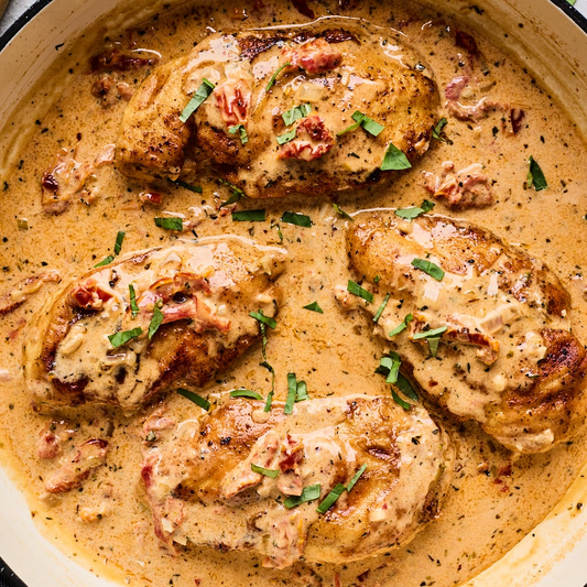 Chicken breast in a creamy sauce with herbs in a pan 